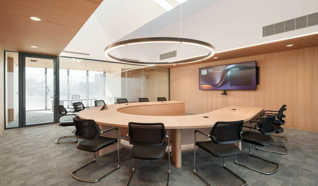 Sala de reuniones con tecnología integrada, pantalla de gran formato y sistema de videoconferencia